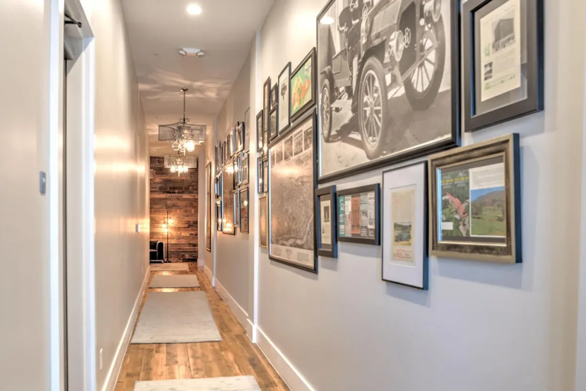 A bright hallway showcasing a gallery wall filled with framed art, complemented by a wooden floor and elegant chandelier. This transitional space hints at the property's location in a vibrant, artistic downtown context.